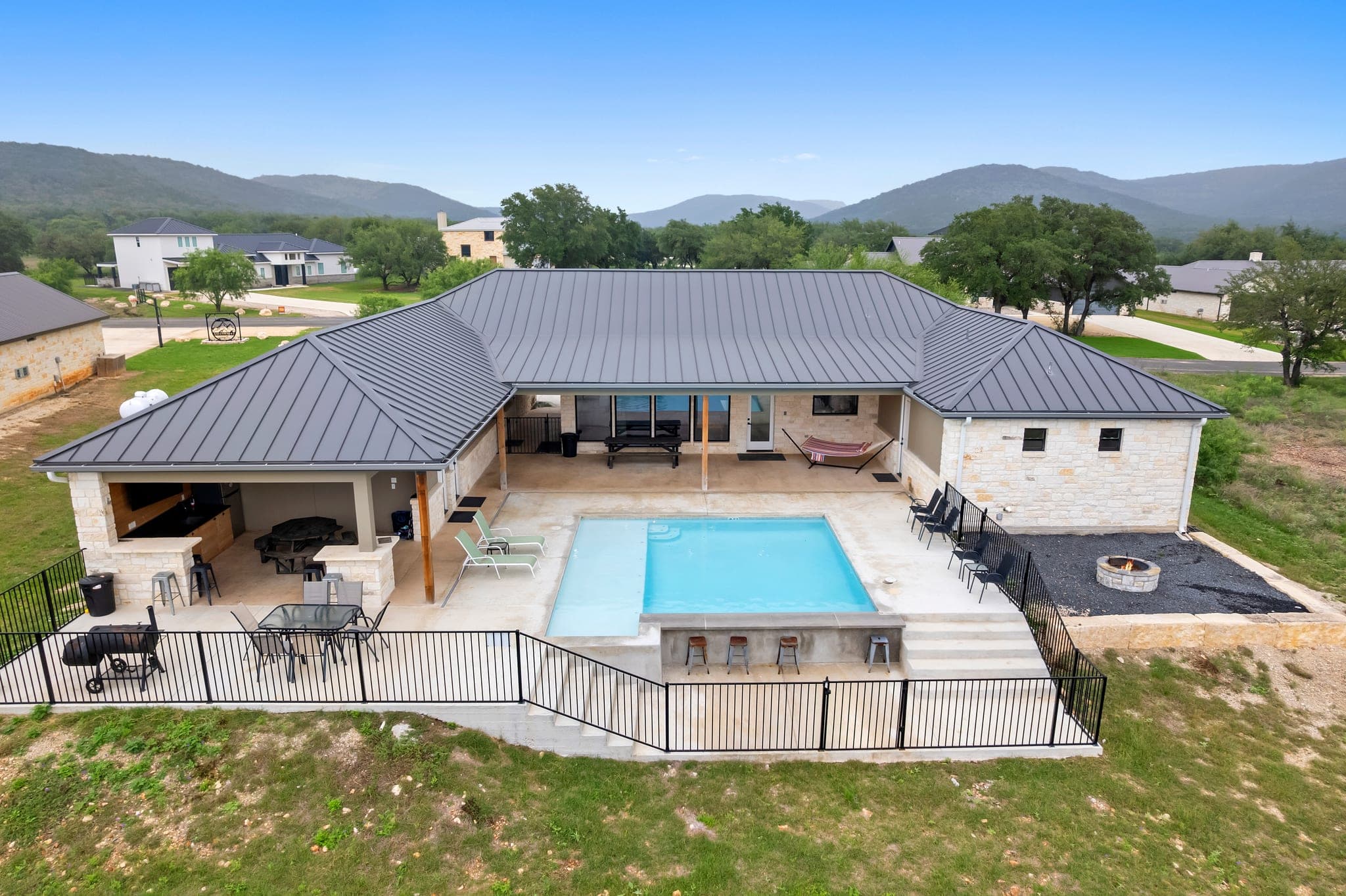 Aerial view of a modern home, pool, and surrounding acreage