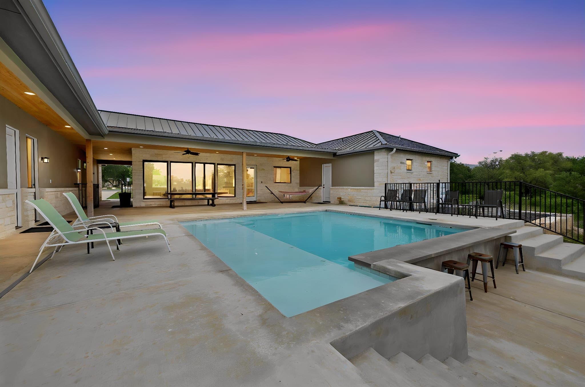 Modern pool and covered outdoor living area at twilight